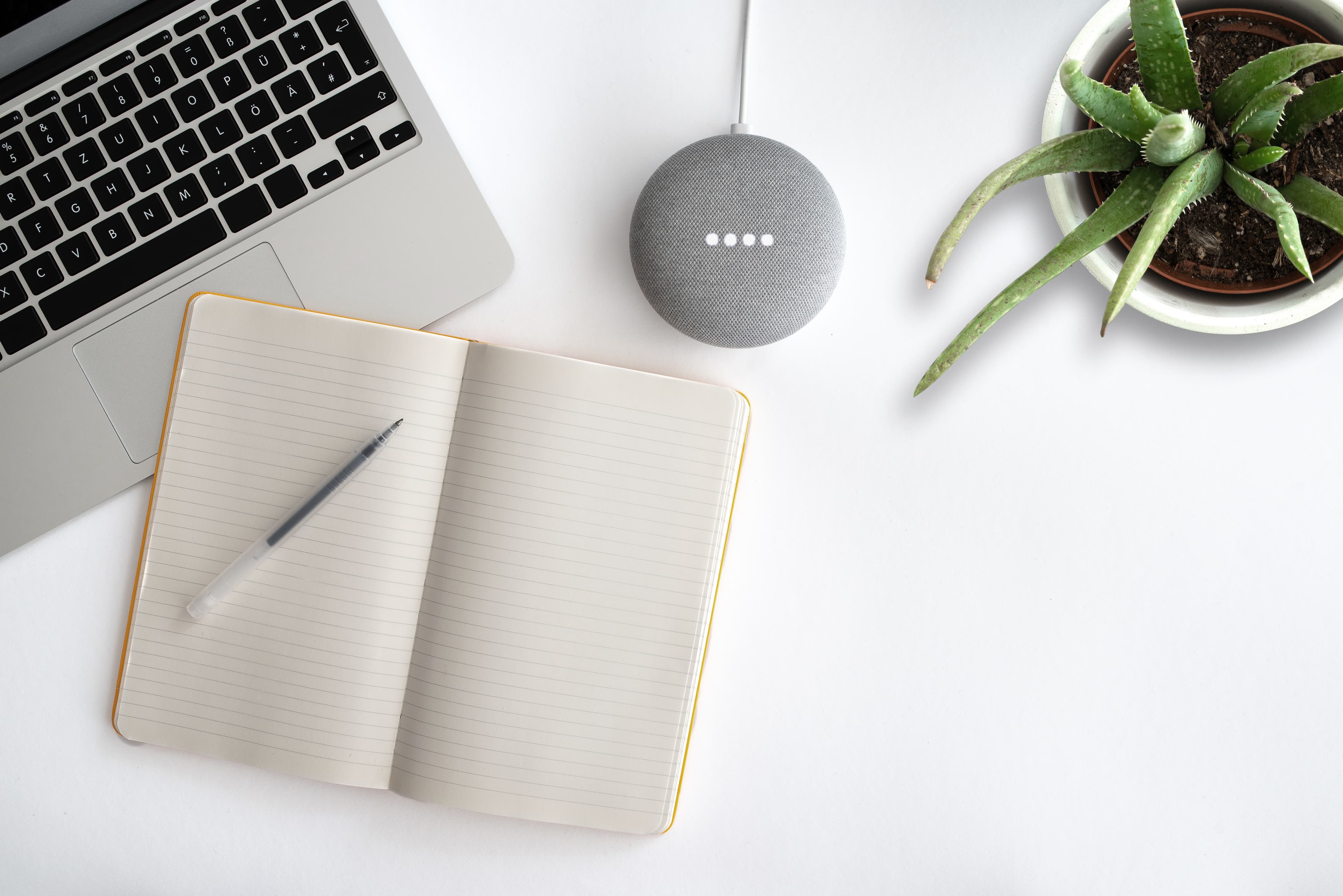 Cahier de notes avec ordinateur et assistant vocal sur un bureau